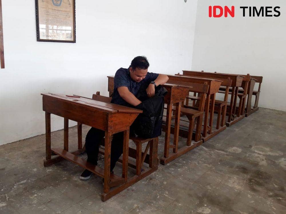 Salah seorang pengunjung menjajal bangku dan kursi kelas zaman dulu di Museum Pendidjkan. IDN Times/Fitria Madia