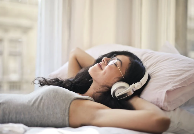 ilustrasi wanita sedang mendengarkan musik di tempat tidur (pexels.com/Andrea Piacquadio)