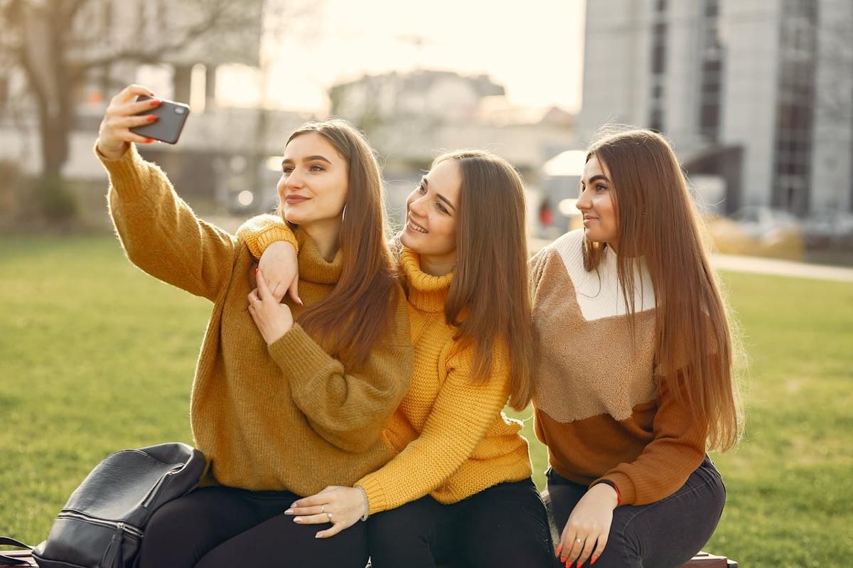 Tiga orang wanita sedang melakukan selfie di taman.