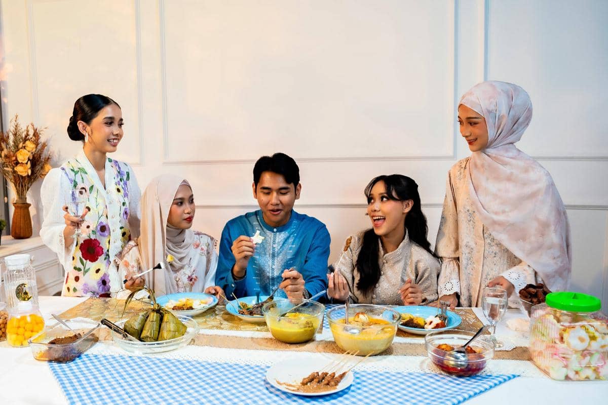 Keluarga Muslim berkumpul di meja makan saat berbuka puasa Ramadan, mengenakan busana muslim dan menikmati hidangan khas berbuka