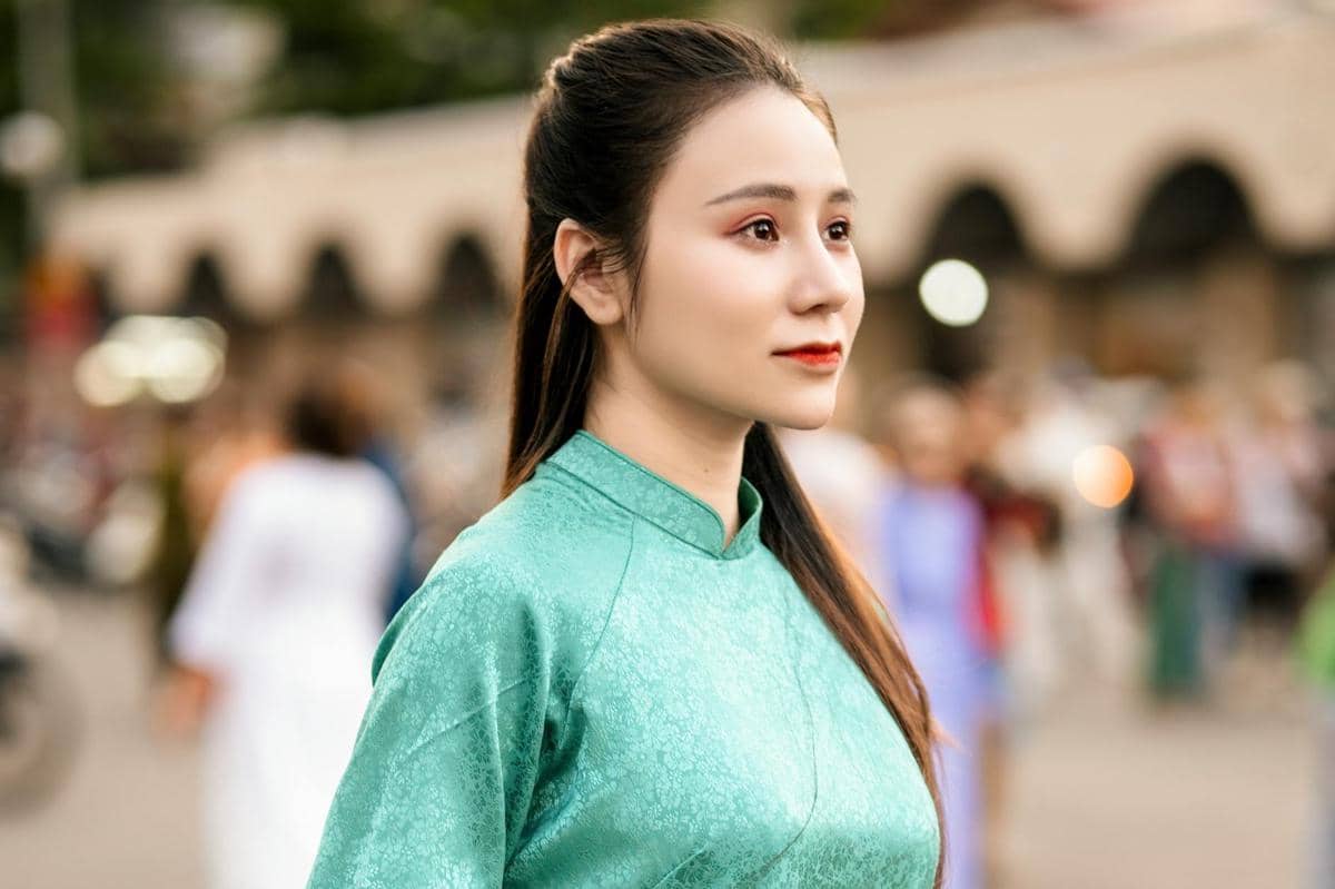 Seorang perempuan mengenakan cheongsam atau qipao berwarna hijau.