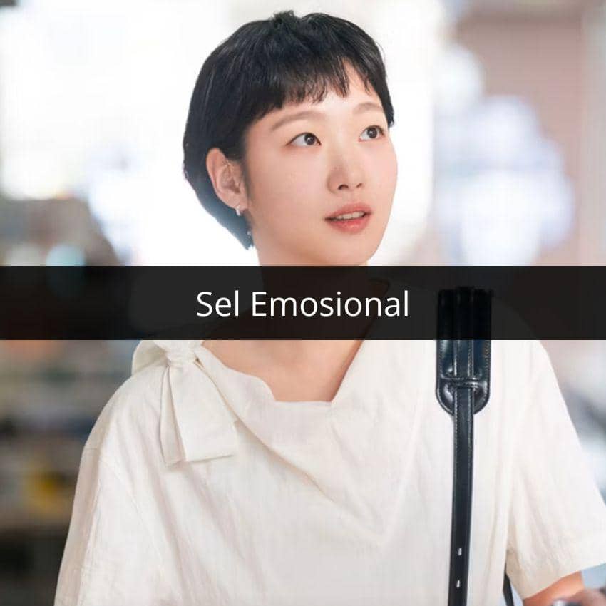 Perempuan berambut pendek mengenakan blus putih dengan latar belakang kabur dan tulisan 'Sel Emosional' di bagian tengah gambar.