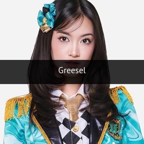 Seorang anggota grup idola mengenakan kostum panggung berwarna biru toska dengan hiasan pita di rambut dan dasi emas.