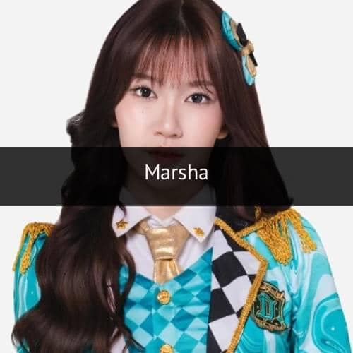 Seorang anggota JKT48 mengenakan kostum panggung berwarna biru dan emas dengan dasi emas dan aksesori rambut senada.