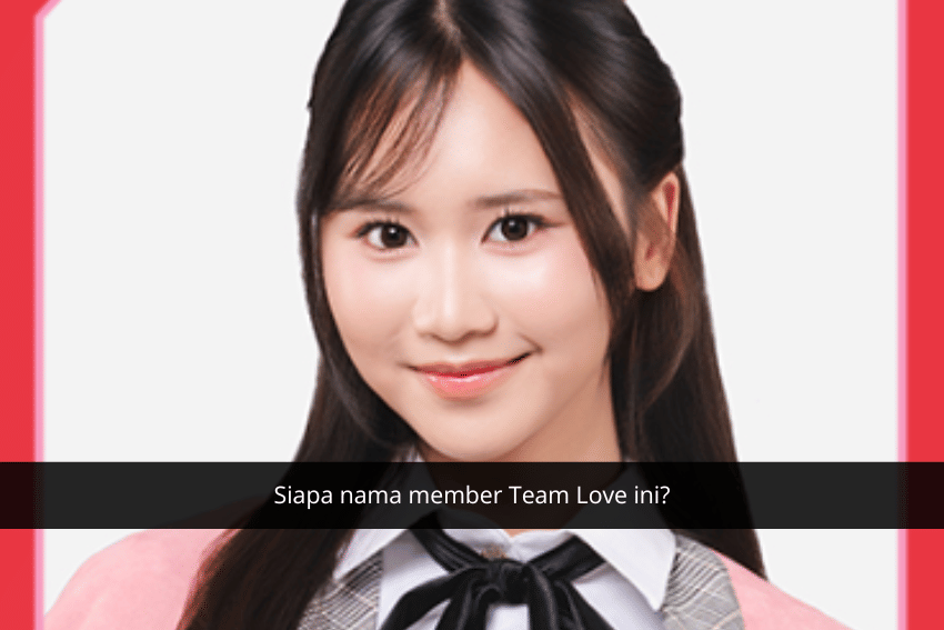Seorang member Team Love JKT48 mengenakan seragam berwarna abu-abu dengan pita hitam dan cardigan merah muda, tersenyum ke arah kamera.