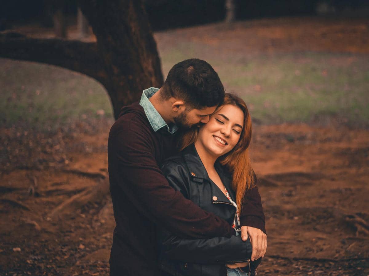 Pasangan kekasih berpelukan mesra di taman dengan suasana hangat dan romantis