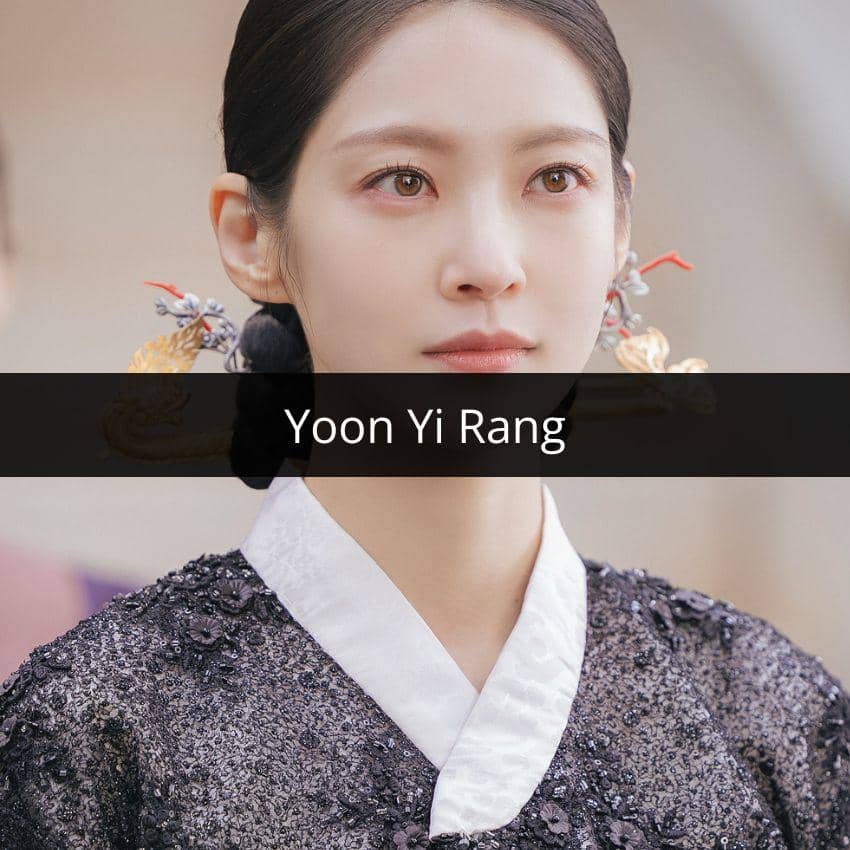 Seorang wanita mengenakan hanbok berwarna hitam dan putih dengan hiasan rambut tradisional, tampak menatap ke depan dengan ekspresi tenang.