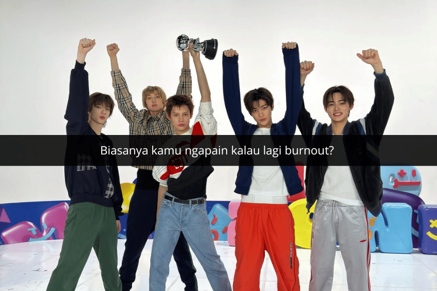 Lima pria muda berpose dengan tangan terangkat, salah satunya memegang piala, di ruangan berwarna cerah dengan latar dekoratif.