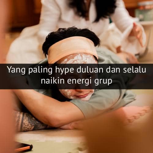 Seseorang berbaring santai dengan masker wajah dan ikat kepala, tersenyum saat menikmati waktu perawatan diri di dalam ruangan.