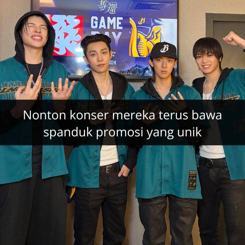 Empat anggota grup musik pria berpose bersama mengenakan jaket biru kehijauan di depan layar bertuliskan Game Day.