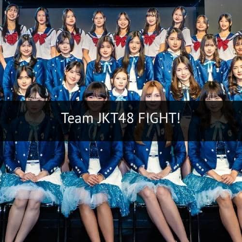Para anggota grup idola JKT48 berpose bersama mengenakan seragam panggung berwarna biru dan putih dengan latar panggung hitam.