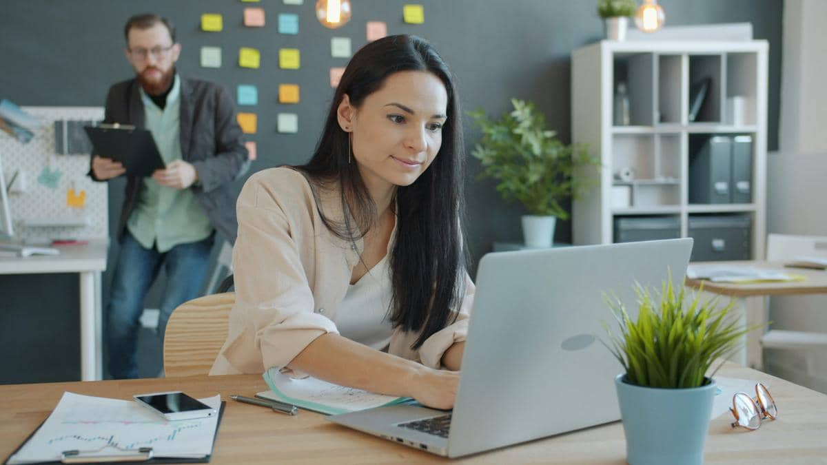 woman working on laptop with man behind her
