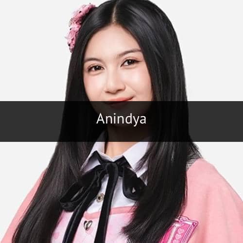 Seorang perempuan berambut panjang mengenakan seragam berwarna merah muda dengan pita hitam dan aksesori bunga di rambutnya.