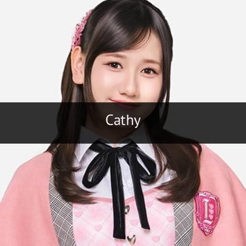 Seorang anggota grup idola JKT48 mengenakan seragam berwarna pink dan abu-abu dengan pita hitam serta aksesori rambut berwarna senada.