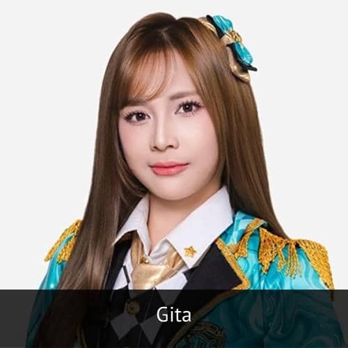 Seorang perempuan berambut panjang mengenakan seragam berwarna biru dengan hiasan emas dan pita di rambutnya, berpose di latar polos.