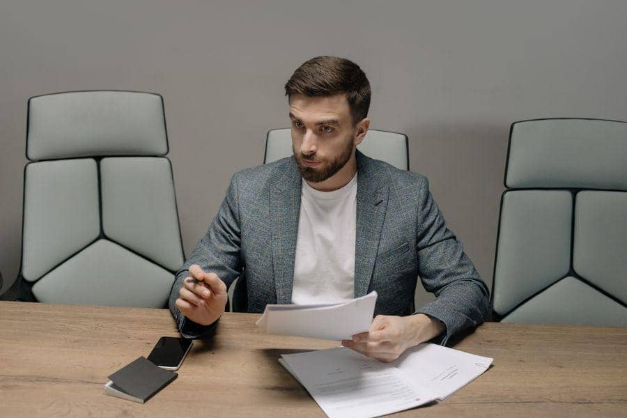 https://www.pexels.com/photo/bearded-man-wearing-suit-jacket-holding-papers-6814538/