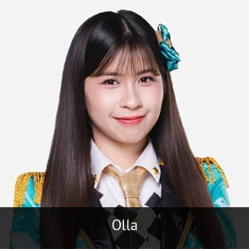 Seorang anggota JKT48 bernama Olla mengenakan kostum panggung berwarna hijau dan emas dengan dasi emas serta pita di rambutnya.