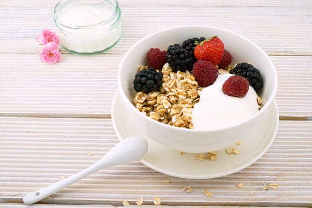 Semangkuk yogurt dengan granola dan buah beri yang kaya protein untuk mendukung pertumbuhan dan pemukihan otot.