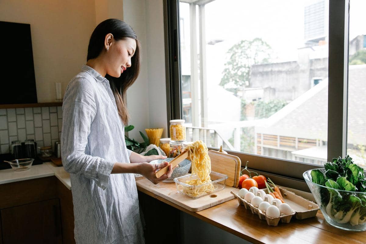Wanita memasak pasta di rumah.